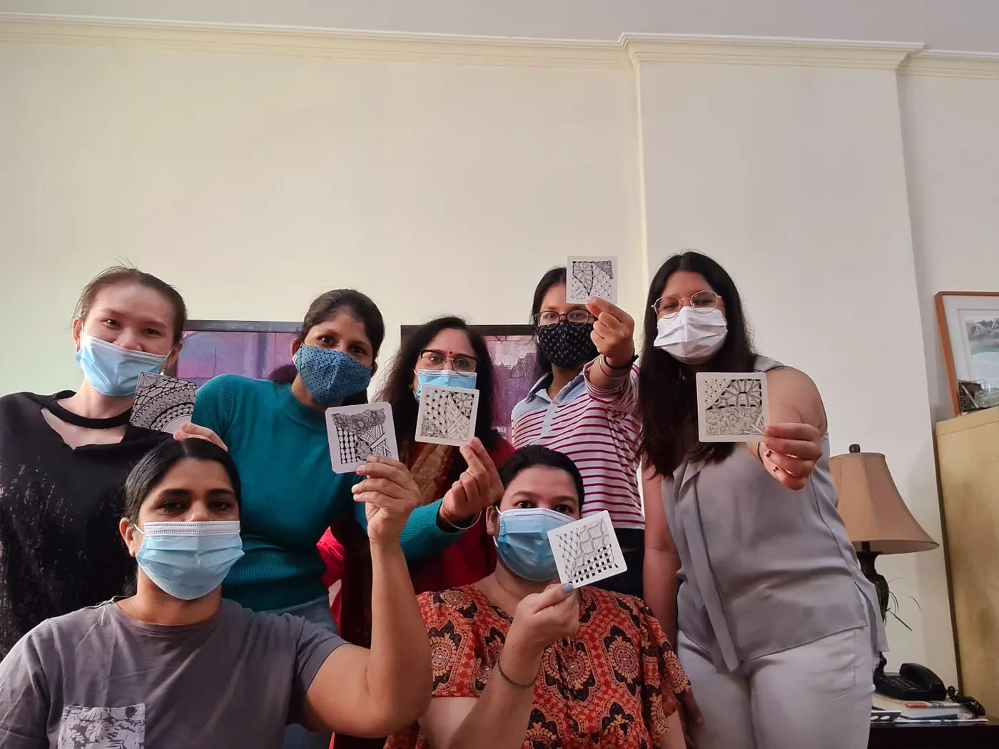 Workshop participants proudly holding up their finished Zentangle tiles